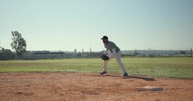 Görünmeyen atış, eldivenli bir erkek oyuncuyu ilk kalede kaydırıyor, oyunu takip etmek için koşuyor. Sporcu, spor, aksiyon, açık hava, rekabetçi, stadyum, hareket