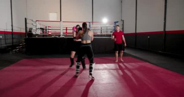 Gardiyan pozisyonunda bayan dövüşçüler, koç minderde durana kadar eldivenle tekmeliyorlar. Dövüş, antrenman, dövüş, fitness, aksiyon, yarışma