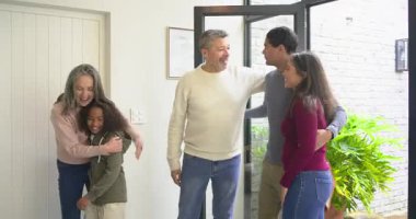 Cam kapı, çeşitli ailelerin hediye kutusunu uzattığı ve aile girişini kucakladığı şekilde içeri doğru sallanıyor. Aile, selamlaşma, ev, bağlantı, sıcaklık, kutlama, iç mekan.