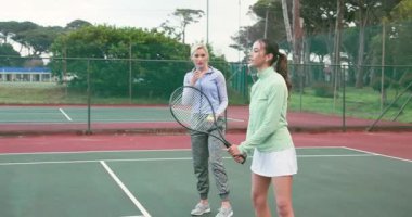 Koç, forehand talim atışını, öğrencilerin sahada raket sallamasını açıklıyor. Eğitim, spor, spor, spor, açık hava, takım çalışması, aktif, öğretim