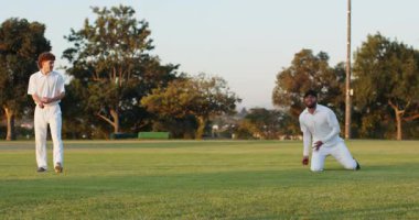 Bovling topuna tepki veren erkek saha oyuncusu, geri dönmek için kırmızı deri topu güvenceye almak için dalıyor. Atletizm, takım çalışması, sportmenlik, aksiyon, eğlence, açık hava, dinamik