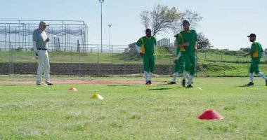 Kıdemli koç, Afrika kökenli Amerikalı erkek oyuncuların sahada kozalakların etrafında koşmasını sağlıyor. Atletizm, antrenman, spor, spor, hareket, ilerleme, takım çalışması