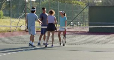 Saray ağlarına doğru yürüyor, çeşitli tenis arkadaşları el sıkışıyor ve adil oynamak için raket vuruyor. Enerjik, enerjik, takım çalışması, yoldaşlık, açık hava, dinamik, atletik