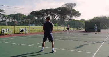 Top sektirme, Asyalı erkek oyuncunun tenis rallisini izlemesine, partnerin işaret planına net olarak katılmasına neden oluyor. Atletik, rekabet, takım çalışması, açık hava, spor, yoğunluk, strateji