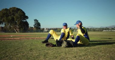 Gelen iki takım arkadaşına hoş geldin diyoruz. Erkek beyzbol oyuncuları çantalarını açıyor ve çimlerin üzerinde geriniyorlar. Sporcular, takım çalışması, açık hava, güneş ışığı, aktif, yoldaşlık, fitness