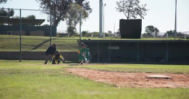 Atıcı atış vuruşunu yapıyor, vuruşunu yapıyor, topa vuruyor ve ilk kaleye koşuyor. Eylem, spor, atletizm, rekabet, takım çalışması, açık hava, canlı