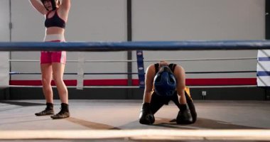 Dişi boksör, pembe giyinmiş rakip ringde kutlama yapıyor ve koçu ringde teselli ediyor. Atletik, rekabet, kararlılık, esneklik, takım çalışması, zafer, eğitim