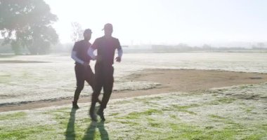 Beyzbol antrenmanından önce erkek oyuncuları sahada çalıştırmak elinde not panosu olan koça, kopyalama alanına. Sporcular, takım ruhu, antrenman, açık hava, gün doğumu, motivasyon, yoldaşlık