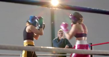 Koçun sinyaline tepki gösteren beyaz kadın boksörler yumruk, kanca ve boks ringinin içinde tezgah değiştiriyor. Atletik, kararlılık, rekabet, eğitim, dayanıklılık, strateji, spor