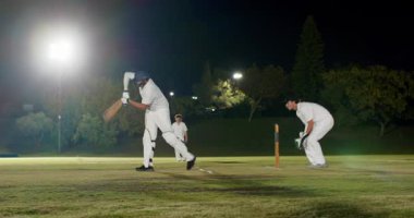 Bowlingci şelale sahasında, Hintli vurucu temyiz ve koşu koşusunu kutlamak için koşuyor. Kriket, gece, sportmenlik, rekabet, atletizm, arena, takım