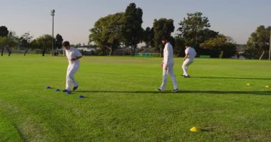 Atış kronometresi, çeşitli erkek spor takımları ısınmak için spor sahasında çeviklik tatbikatı yapıyor. Atletizm, antrenman, spor, takım çalışması, koordinasyon, açık hava, spor