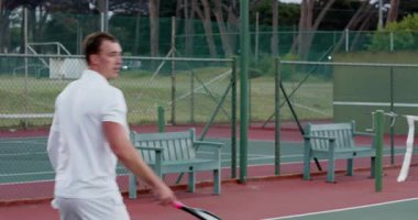 Rakibi, Asyalı erkek oyuncunun açık havada raketle yaylım ateşine karşılık vermesini sağlıyor. Spor, rekabet, takım çalışması, aktif giysi, açık hava, atletizm, hassasiyet