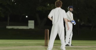 Top tutucu, bowling oyuncusu ve çeşitli erkek takımlarının sahne ışıkları altında kaleye başvurması. Spor, takım çalışması, zafer, performans, aksiyon, rekabet, arena