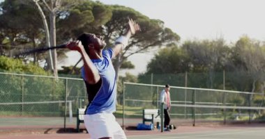 Vuruş yapan Afro-Amerikan bir adam ve tenis kortuna dönen bir kadın. Atletik, rekabet, açık hava, enerjik, koçluk, çeviklik, profesyonellik