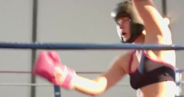 Başlıklı iki kadın boksör, ringde yumruk tokuşturuyor, kancaları iplere takıyor. Atletik, dövüş, güç, rekabet, esneklik, eğitim, fitness