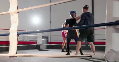 Antrenör ringde ip tamir ediyor, ped takıyor antrenman için antrenman yapıyor, siyah boksör kollarını kaldırıyor. Boks, antrenman, fitness, spor, atletik, güç, disiplin