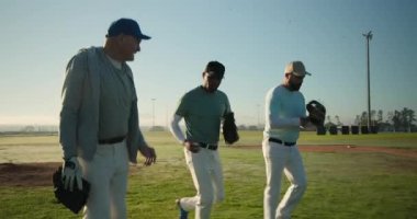 Yürüyüş koçu ve iki oyuncu şafak vakti atış sahasına ulaşarak beysbol tutuşunu gösteriyor. Atletizm, eğitim, akıl hocalığı, takım çalışması, canlı, motivasyon, açık hava