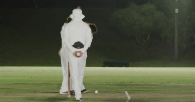 Çekici erkek kriketçiler topun alınması ve kefaletle serbest bırakılması için baskı yapıyor, şelalenin altında kaleye tezahürat yapıyor. Performans, takım çalışması, zafer, atletizm, açık hava, rekabet, strateji