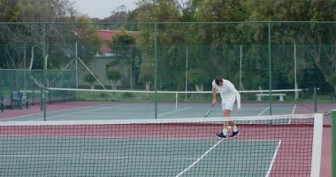 Tenis kortunda top ve raketlerle servis ve voleybol antrenmanı yapan farklı erkek ikilisi. Spor, eğlence, atletizm, rekabet, eğitim, açık hava, aktif