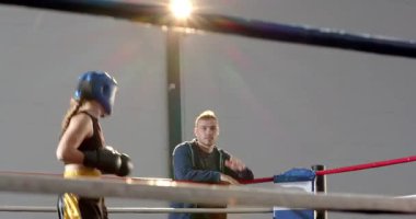 Jimnastik ringinde başlık takan iki kadın boksöre yol gösteren jest koçu. Eğitim, spor, atletizm, kondisyon, spor, performans, disiplin