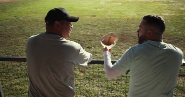Eldivenleri ve şapkaları kaldıran iki orta yaşlı adam beyzbol sahasında tel örgülerin arkasında tezahürat yapıyor. Takım arkadaşları, kutlama, yoldaşlık, açık hava, sportif, enerjik, neşeli