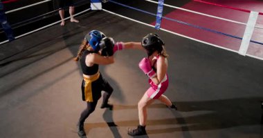 Antrenör, bayan boksörlerin boks antrenmanlarına ve boks sahasında eldivenlerle daireler çizmelerine tepki veriyor. Atletik, dövüş, kararlılık, eğitim, rekabet, güç, disiplin