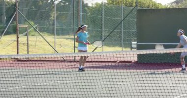 Çeşitli tenis ikililerini top fırlatıp ağ atarak yürüyüş ve açık havada beşlik çakarak. Spor, rekabet, takım çalışması, etkinlik, açık hava, atletizm, canlı