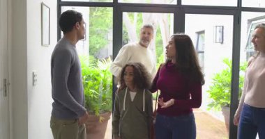 Dönen oğlunu antrede karşılayan aile yeşil hediye kutusu sunuyor ve tavan lambasını işaret ediyor. Aile, eve dönüş, birleşme, kutlama, sıcaklık, birliktelik, aile içi ilişkiler.