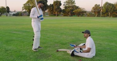 Eldiven sunan ve sopayı alan çeşitli erkek takım arkadaşları, alacakaranlıkta kriket maçına hazırlanıyorlar. Sporcular, takım çalışması, sportmenlik, rekabetçi, açık hava, atletizm, boş zaman