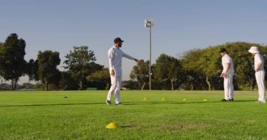 Çeşitli erkek grupları antrenman için çim tarlasında koni karıştırıyor ve zıplatıyorlar. Atletizm, takım çalışması, açık hava sporları, egzersiz, çeviklik, spor, eğitim