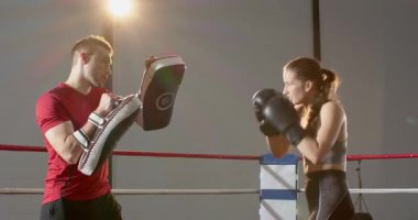 Uzatma eldivenleri, antrenör kadın boksör sıralaması yumruk kroşesi atma ve ringe tekme atma, kopyalama alanı. Dövüş sanatları, fitness, antrenman, spor, kararlılık, güç, disiplin