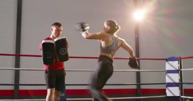 Antrenör yumrukları çağırıyor, pedleri tutuyor, stajyere boks antrenmanında yumruk atma tekmeleri atıyor. Eğitim, güçlendirme, fitness, dövüş, dövüş sanatları, egzersiz, disiplin