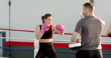 Erkek antrenör kombinasyonları arıyor. Kadın boksör, ringin içinde kroşe atma antrenmanı yapıyor. Kopya uzayı. Atletik, antrenman, güç, zindelik, kararlılık, dinamik, hareket