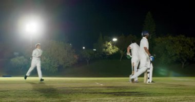 Hintli vurucu arka arkaya koşuyor, kıvılcım saçıyor, kütük kırıyor, erkek üçlüsü geceleri tezahürat yapıyor. Kriket, kutlama, takım, spor, gece, stadyum, yoldaşlık