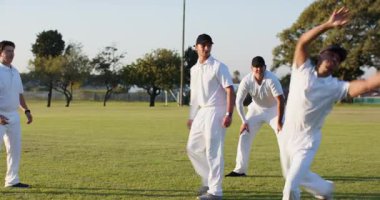 Cırcır böceği topu ve kütükle çimlerin üzerinde çeşitli erkek takımları tarafından el altından fırlatılan saha çalışması. Sporcular, takım çalışması, atletizm, açık hava, eğlence, eğitim, sportmenlik