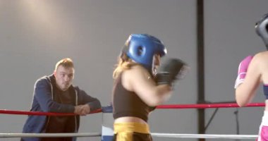 Başlık takan kadın boksörler antrenman için antrenmanı izlerken ringde dönüp duruyorlar. Askerler, savaş, eğitim, atletizm, dayanıklılık, güç, kararlılık