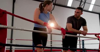 Antrenmandan sonra, kadın sporcu halata yaslanıyor ve erkek koçla stratejiyi tartışıyor. Eğitim, danışmanlık, kararlılık, fitness, spor, motivasyon, yoğunluk