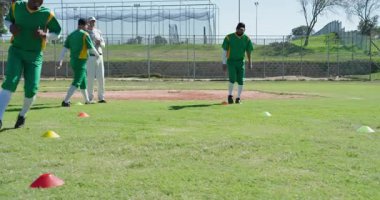 Kronometre antrenörüne başlama zamanı erkek beyzbol oyuncuları sahada külahların etrafında koşturup duruyorlar. Spor, antrenman, çeviklik, spor, açık hava, koçluk, performans