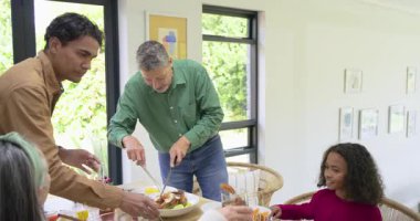 Çeşitli aileler bayram yemeklerini kutluyor kümes hayvanları oyuyor ve masada mısır ve taze fasulye servis ediyorlar. Aile, kutlama, yemek, şenlik, birliktelik, sıcaklık, gelenek