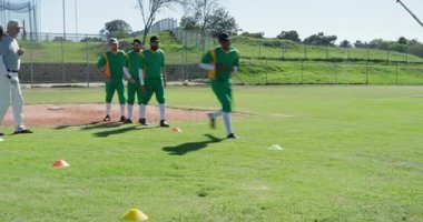 Koç sinyali alıyoruz, çeşitli erkek beyzbol takımları güneş ışığında beyzbol sahasında koni talimi yapıyorlar. Atletizm, antrenman, takım çalışması, spor, performans, açık hava, spor