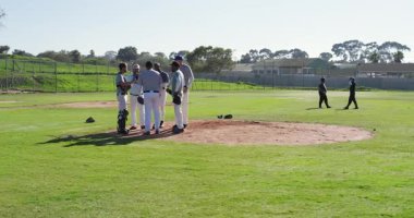 Sahada toplandıktan sonra eldivenli çeşitli erkek takım arkadaşları sahaya doğru koşuyor ve çerçeveden çıkıyorlar. Sporcular, takım çalışması, açık hava, canlı, rekabetçi, spor, birlik