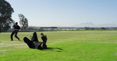 Beyzbol topu fırlatılıyor, beyaz erkek saha oyuncuları koşuyor, sıçrıyor, dış sahada eldiven takıyor. Atletizm, takım çalışması, hareket, aktif, açık hava, uyum, rekabetçi