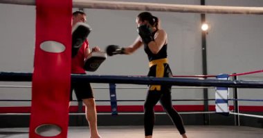 Eğitmen pedleri, boksör kadın yumrukları, çapraz yumruklar ve boks ringlerinde tekmeler, kopyalama alanı. Eğitim, fitness, mücadele, güçlendirme, stüdyo, kuvvet, kararlılık