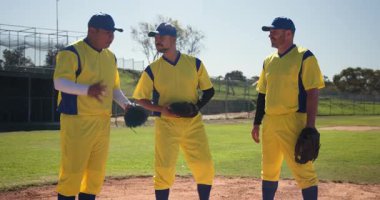 Yeşil eldiveni kaldıran, farklı erkek beyzbol takım arkadaşları eldiveni fırlatıp sahaya doğru yürüyorlar. Sporcular, takım çalışması, yoldaşlık, sportmenlik, açık hava, enerjik, gündelik