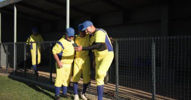 Akıllı telefonlar, farklı erkek beyzbol takımları sahada çitlerle kümeleniyor, gülüyorlar. Sporcular, takım çalışması, açık hava, spor, yoldaşlık, günlük eğlence.