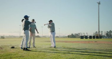 Antrenör sinyaline yanıt olarak çeşitli erkek beyzbol takımları sahada esneyip koni topluyorlar. Atletizm, takım çalışması, fitness, açık hava, spor, eğitim, yoldaşlık