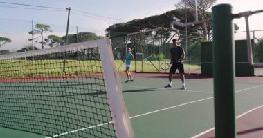 Rakip serviste, çeşitli tenis partnerleri raketlerle volta atıyor. Açık hava, atletik, aktif giyim, spor, takım çalışması, rekabet, spor