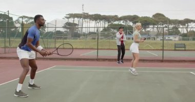 Koçun besleme topu ve çeşitli tenis oyuncularına yol göstermesi. Atletizm, antrenman, sportmenlik, açık hava, odaklanma, teknik, dayanıklılık.