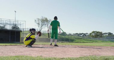 Atıcıdan sonra hızlı top atan erkek vurucu sopayı sallıyor ve ilk kaleye doğru koşuyor. Atletizm, rekabet, hareket, spor, enerji, açık hava, dinamik