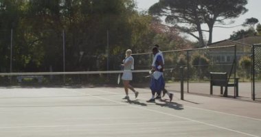 Çeşitli tenis oyuncuları ve koç sahaya giriyor, antrenman için vites indiriyor. Sporcular, açık hava, spor, eğitim, motivasyon, takım çalışması, aktif